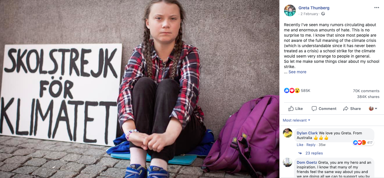 greta thunberg sits on the ground leaning against a stone wall, with a cardboard sign reading 'school strike for climate'